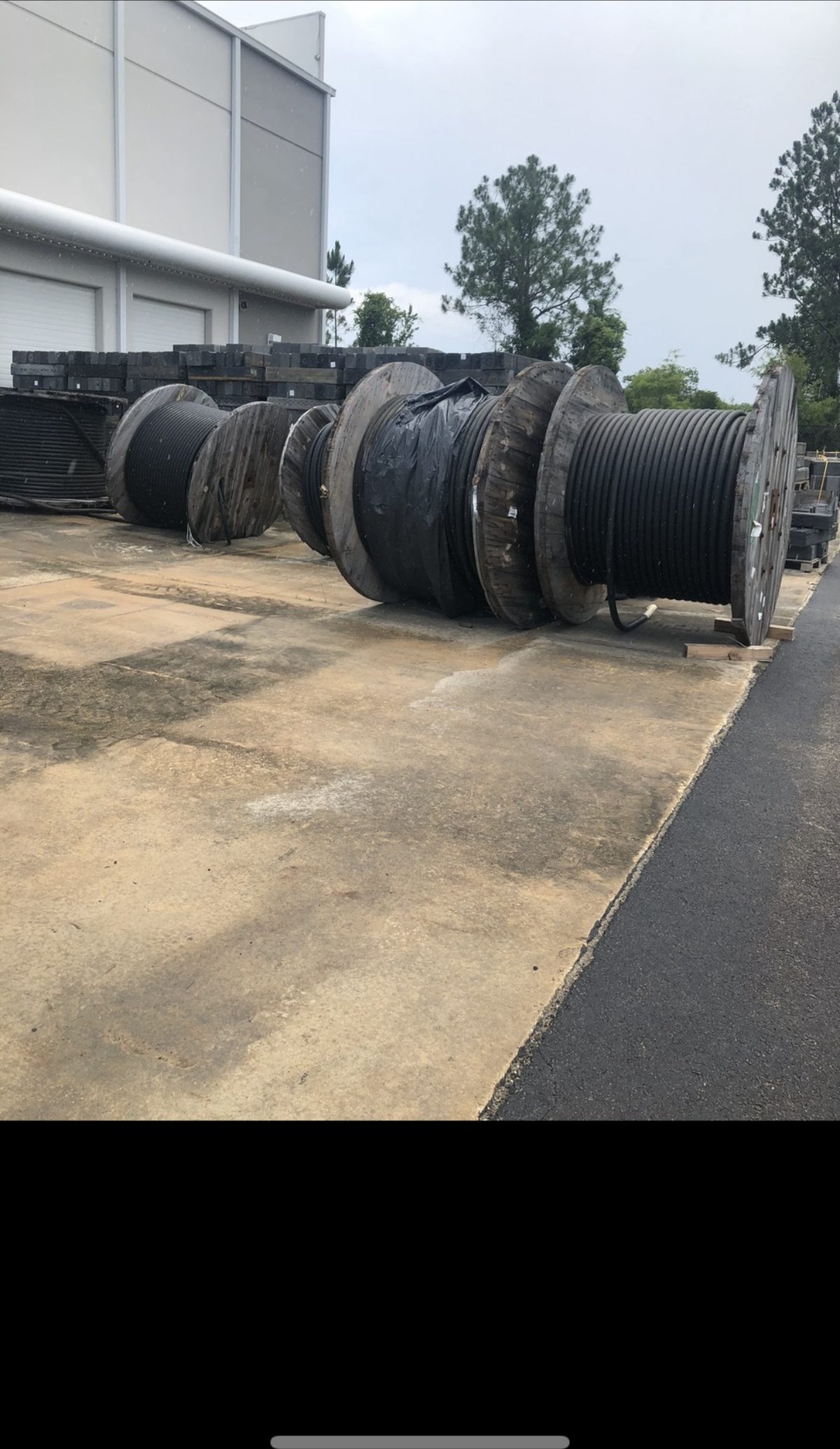 Large surplus electrical cable reels bought outside an industrial warehouse